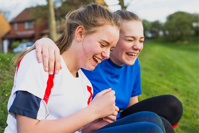 Two girls laughing together in a field