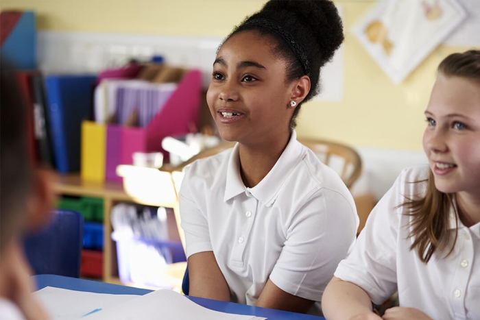 A young girl smiling and looking excited in a classroom