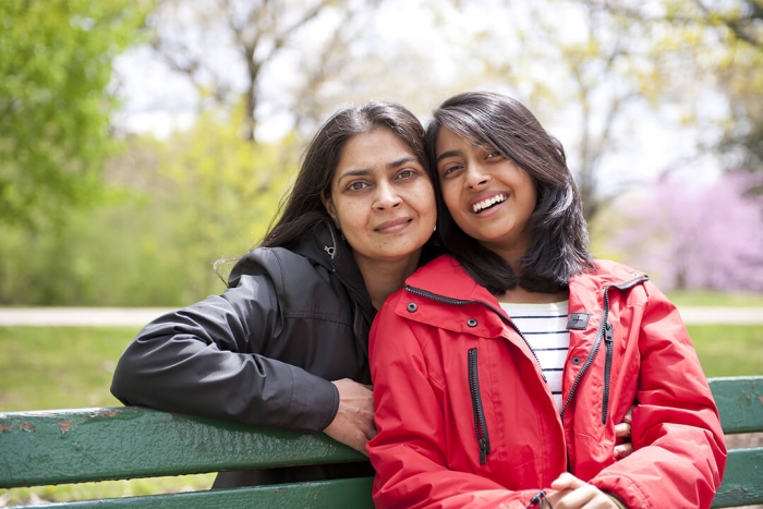 Smiling girl on a park bench with her mother