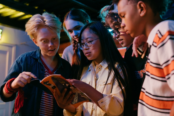 group of young people reading a book